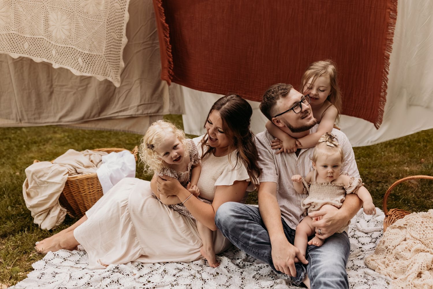 Family sitting together on picnic blanket for outdoor portrait session.