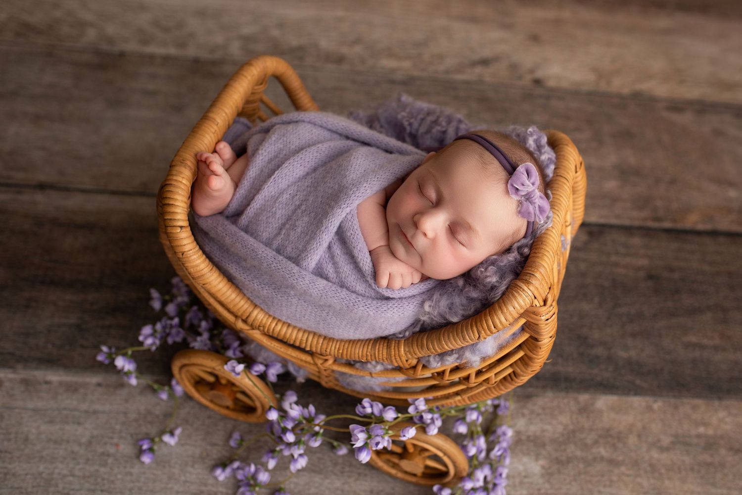 A series of newborn photography shots showing a sleeping baby in a wicker basket surrounded by purple flowers.