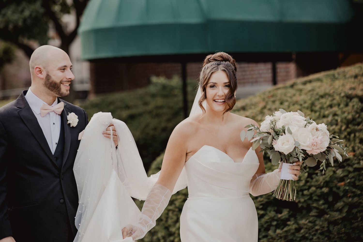 Wedding party members in formal attire gather for photos in a garden setting.