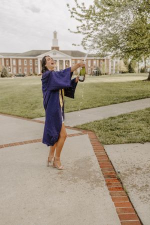 A joyful graduation celebration pose in front of a stately brick university building with columns.