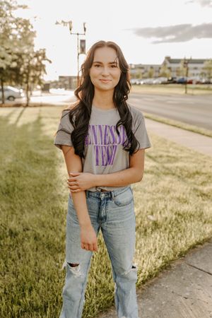 A casual portrait on campus featuring distressed jeans and a graphic t-shirt.