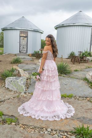 A pink lace wedding dress showcased against white grain silo buildings.