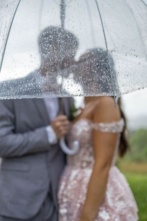 A romantic silhouette under a rain-spotted umbrella captures an intimate moment.