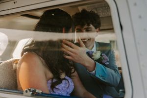 Couple shares intimate moment inside vintage car during prom or formal event.