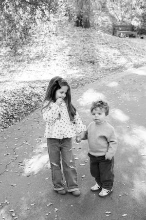 A young girl and her little brohter standing in sunlight on a path in Pasadena California