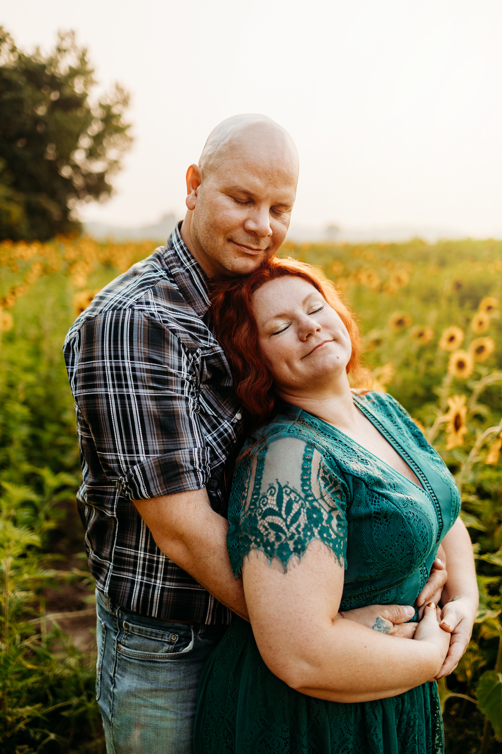 A couple embracing each other in a field of sunflowers.
