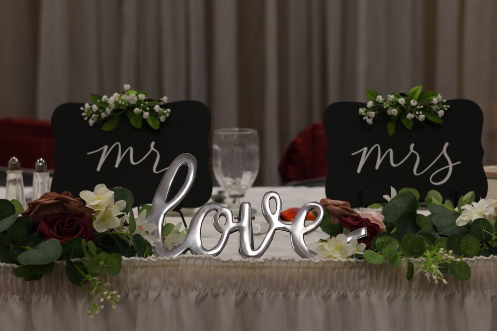 Wedding head table decor featuring 'Mr & Mrs' signs and a decorative 'love' centerpiece.