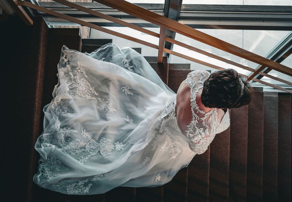 Overhead view of a bride in a flowing lace wedding gown on staircase.