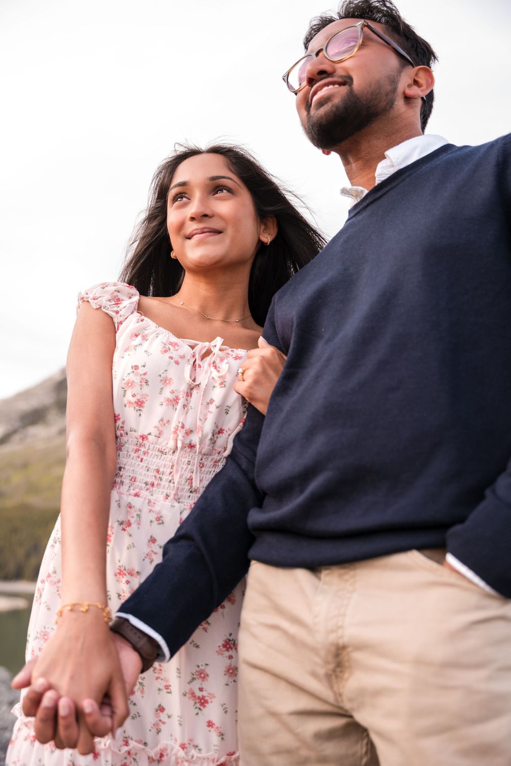 A romantic couple enjoying a mountain vista while embracing in casual outdoor attire.