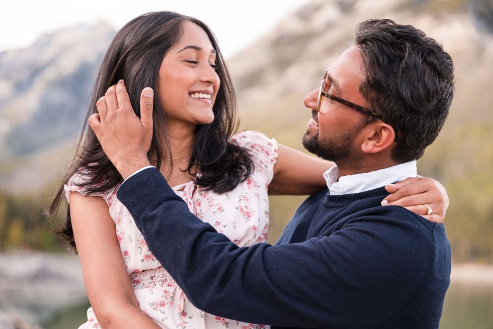 Tender moment captured between couple by scenic mountain lake.