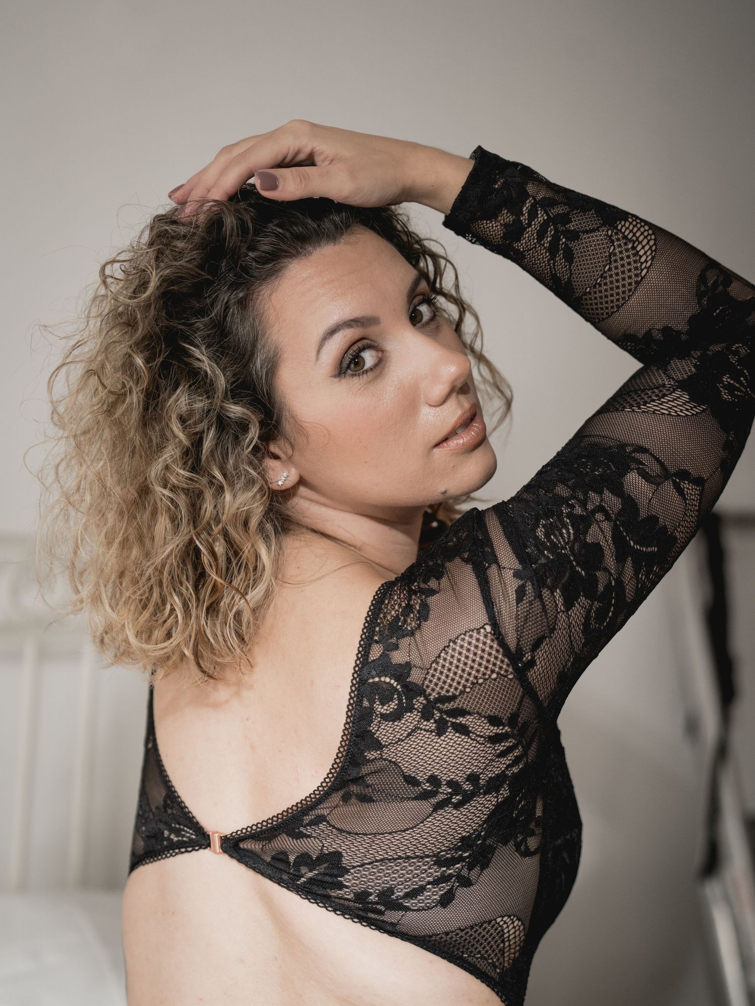 Dramatic boudoir portraits featuring curly hair and black lace against neutral background.
