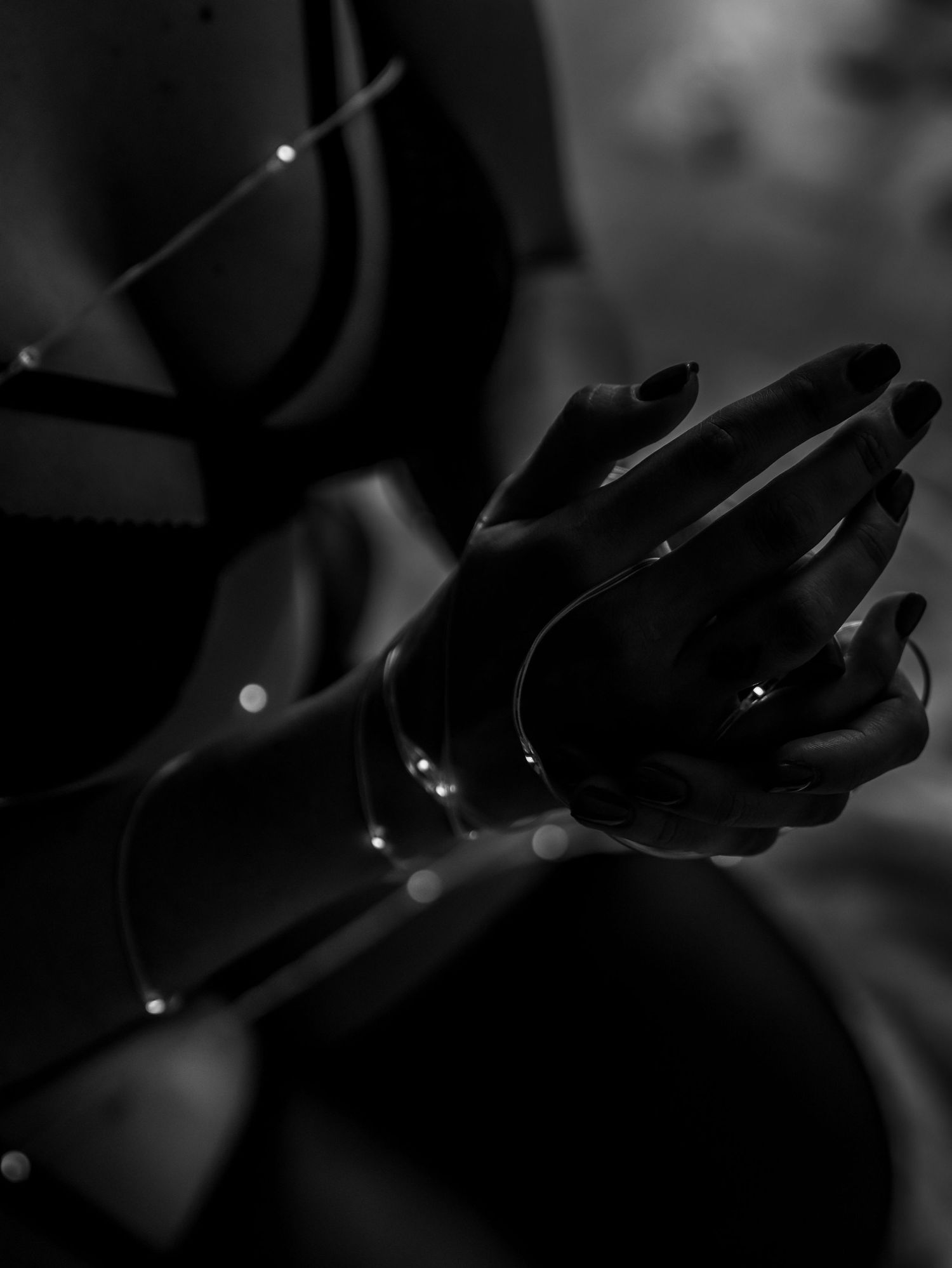 Artistic black and white close-up of hands with sparkles and dramatic lighting.