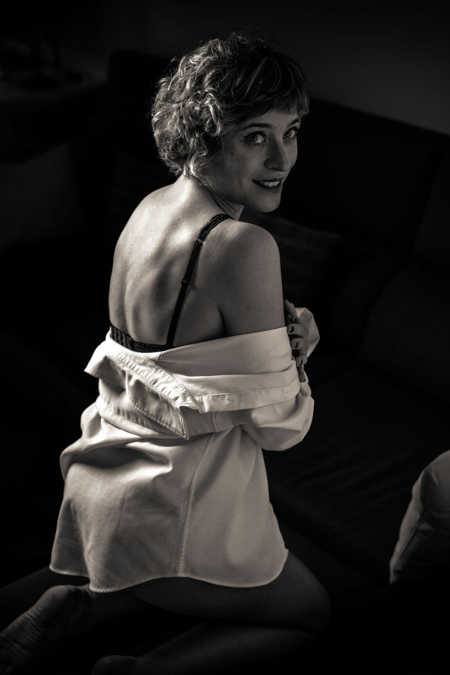 Artistic black and white boudoir portrait showing woman in off-shoulder garment.