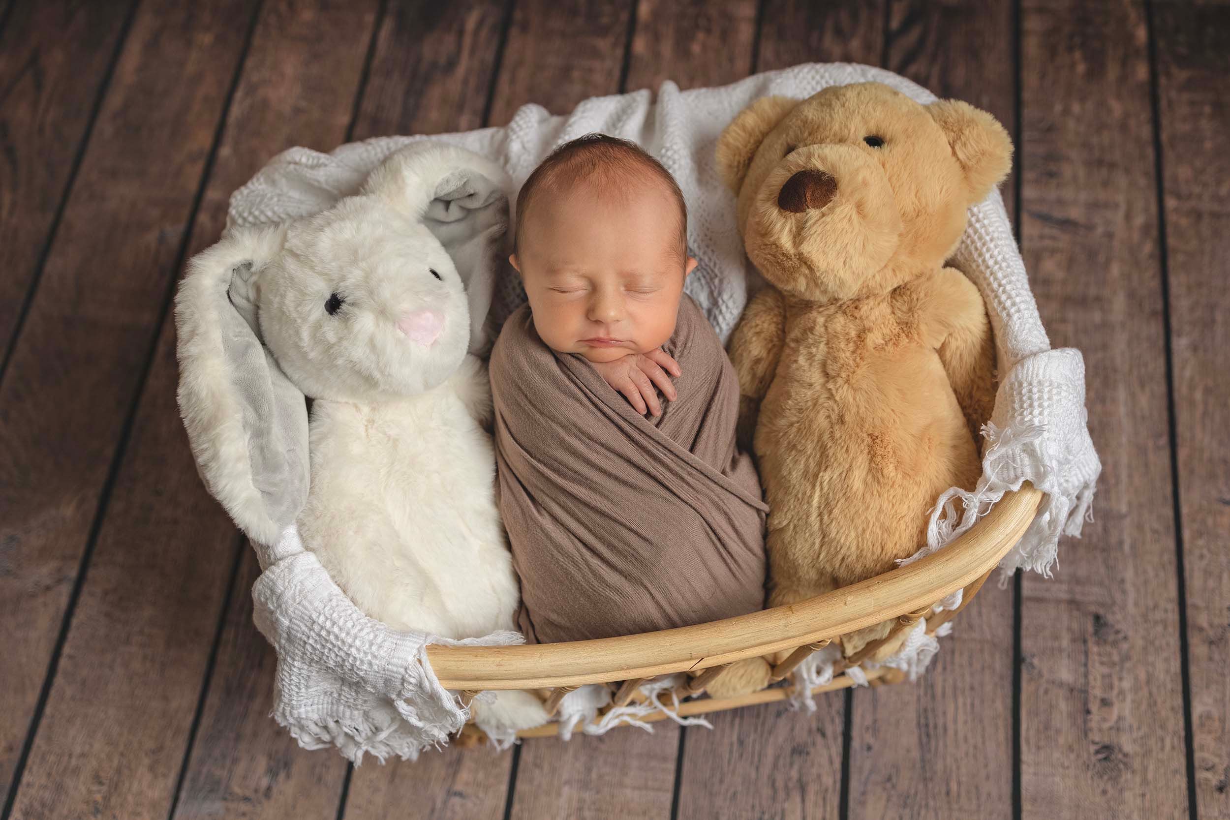 A sleeping baby nestled in a woven basket with two teddy bears. Newborn photographer in Hampshire, baby photos Gosport, newborn fareham