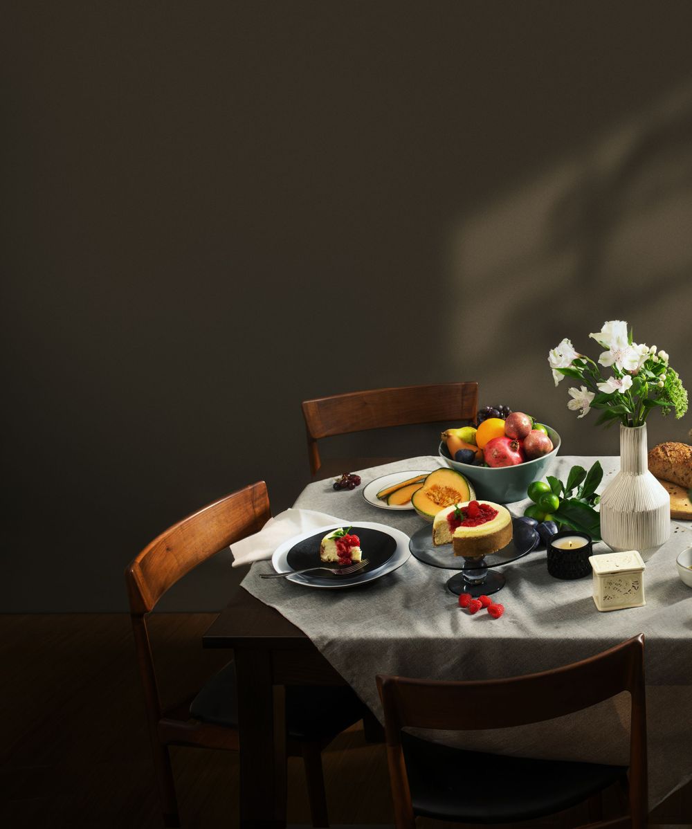 A cozy breakfast table setting with pastries, fresh fruit, and white flowers on a linen tablecloth in warm light.
