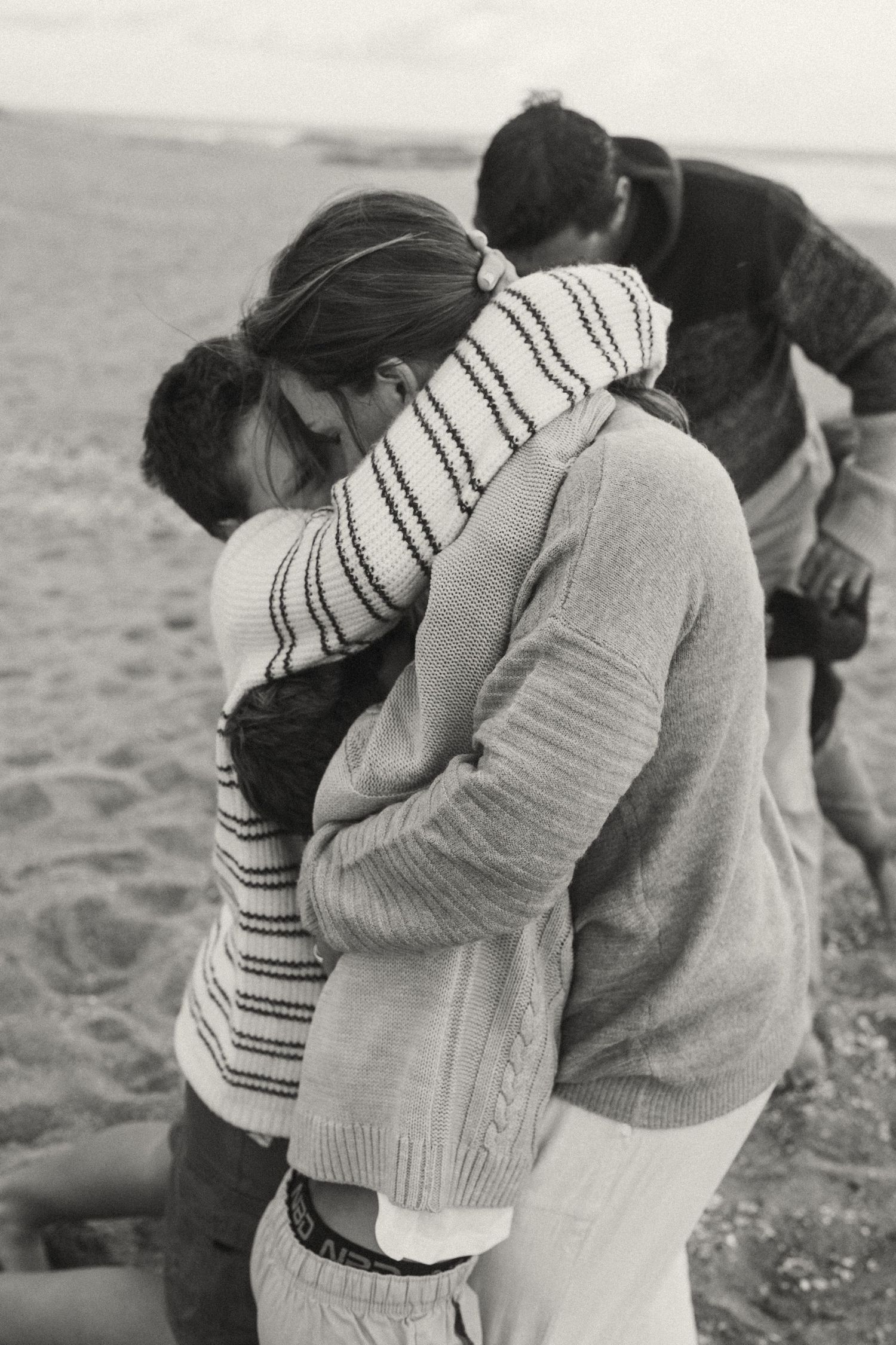 Intimate embraces shared between loved ones on a windswept beach.