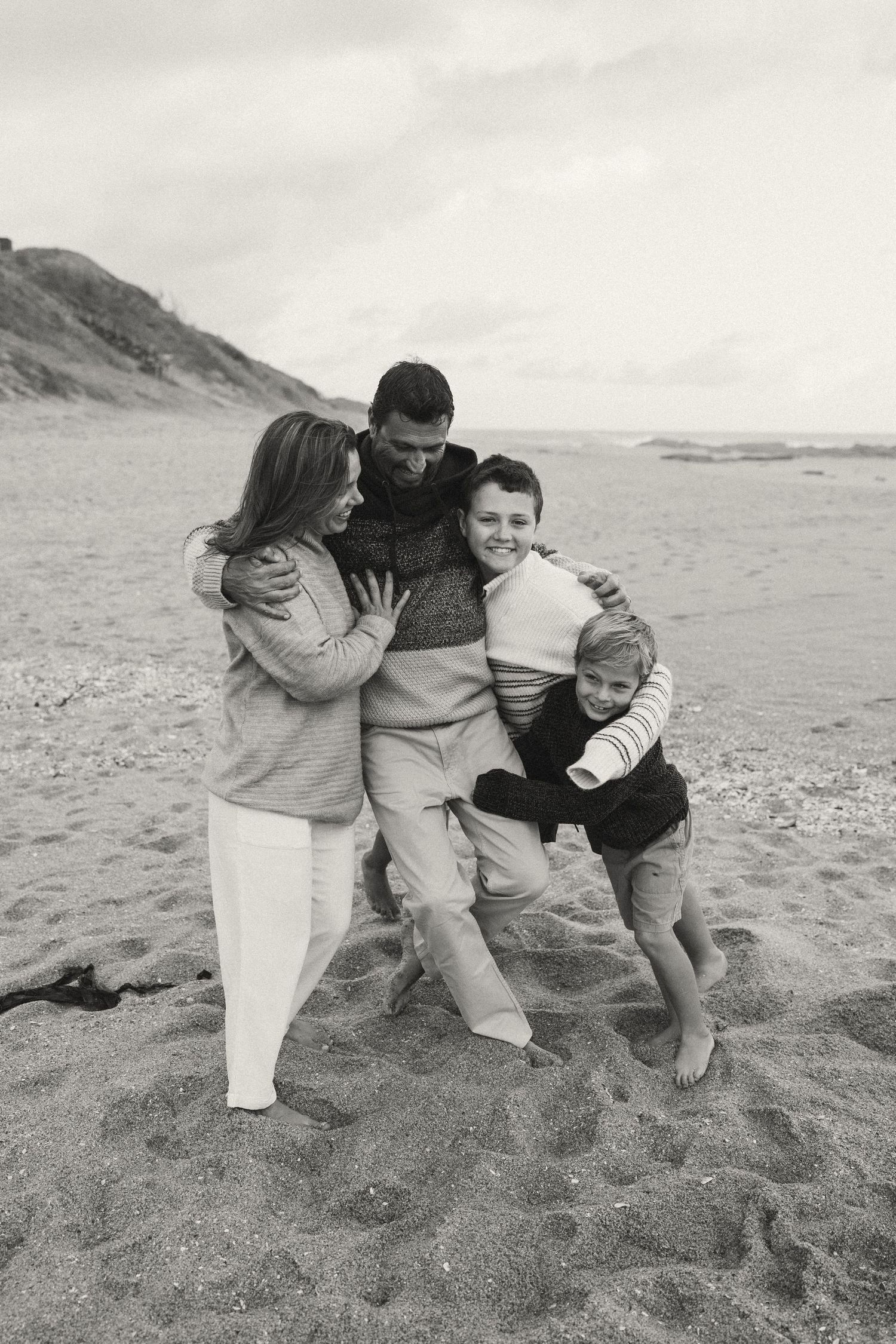 Group huddled together sharing warm embraces on a sandy beach.