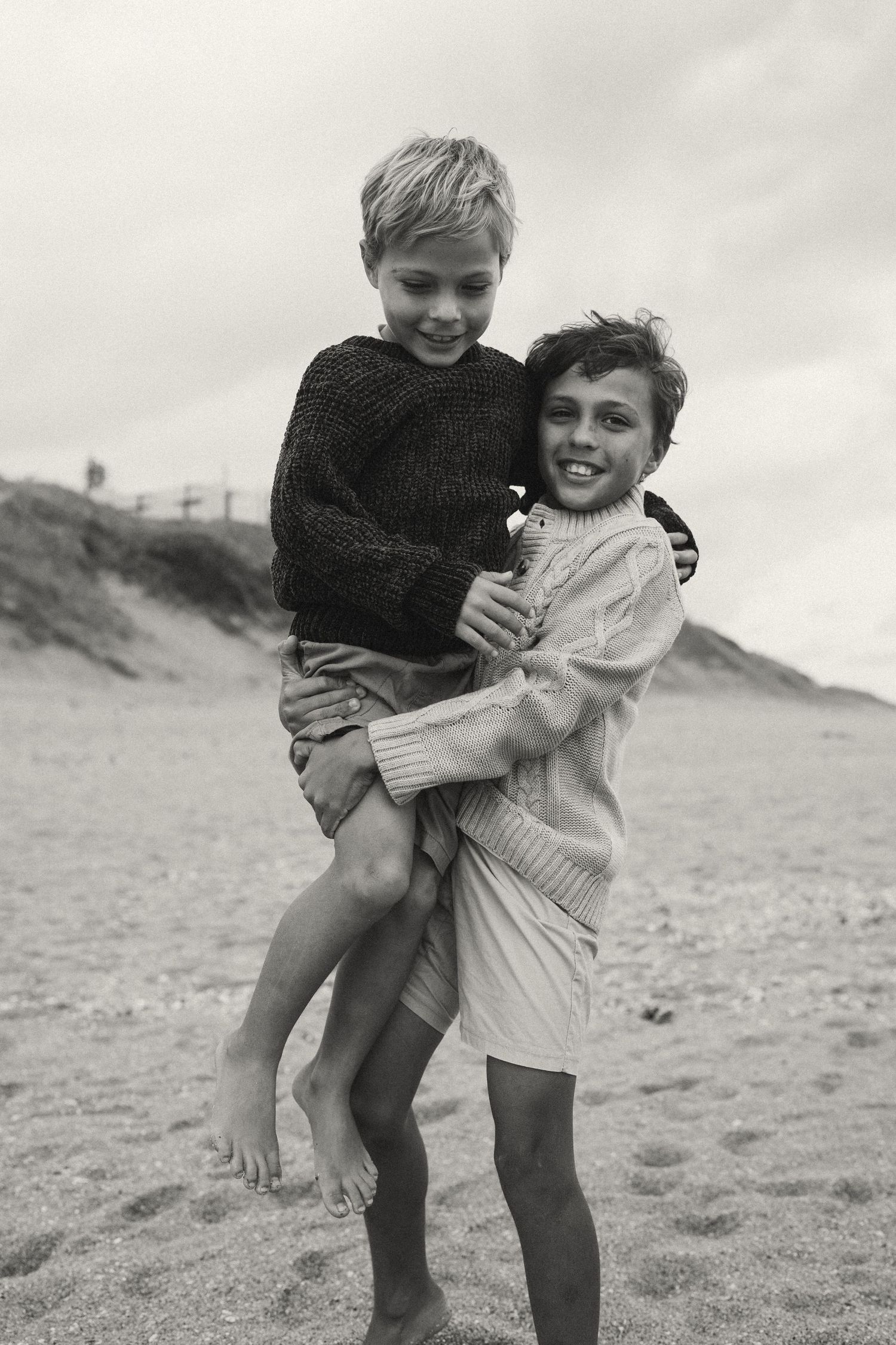 A playful beach scene with family members hugging and lifting each other.