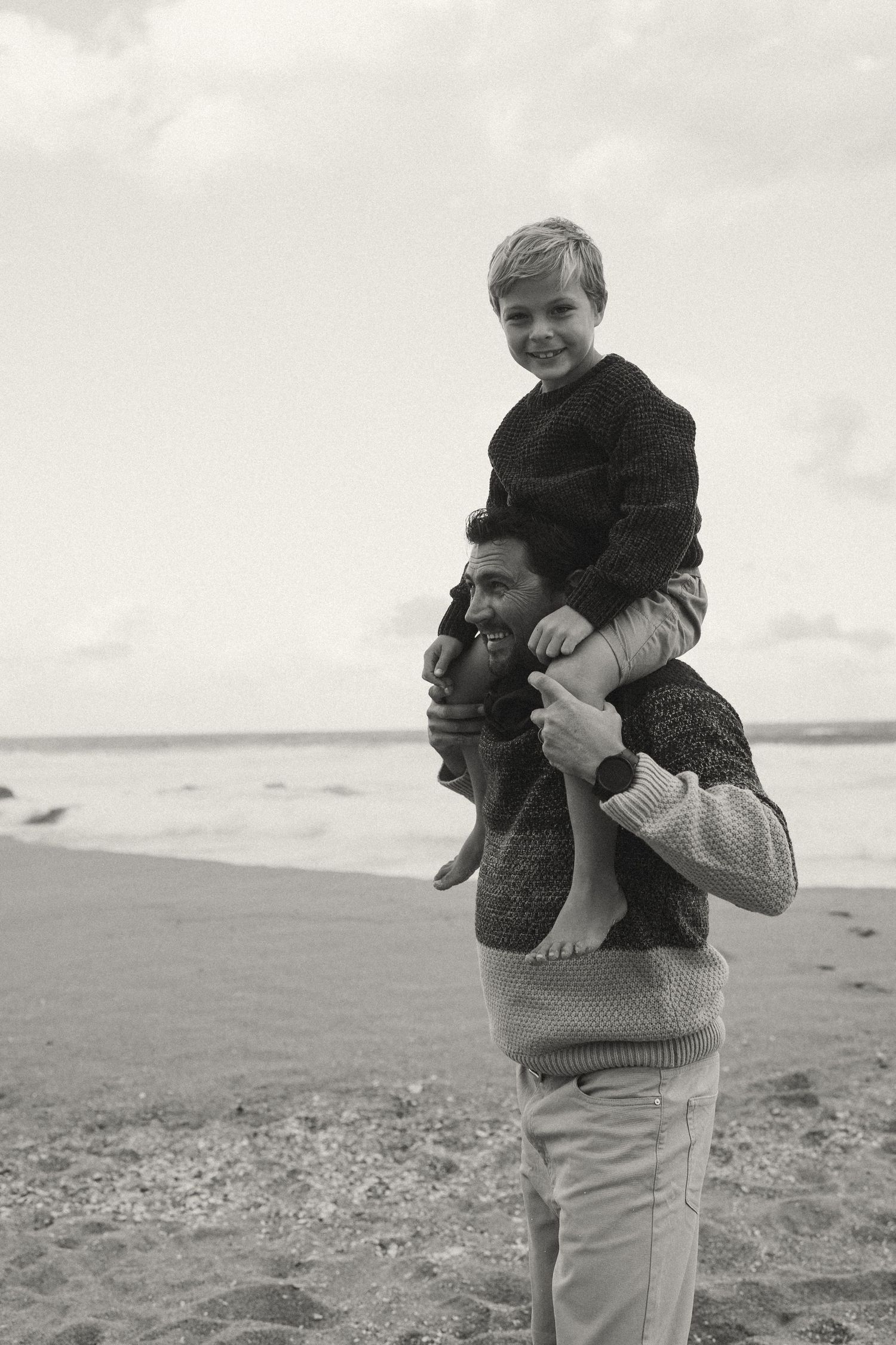 A tender moment between family members embracing on a sandy beach.