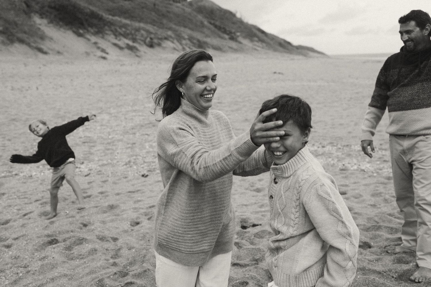 Candid moments of a family playing and laughing together on a sandy beach.