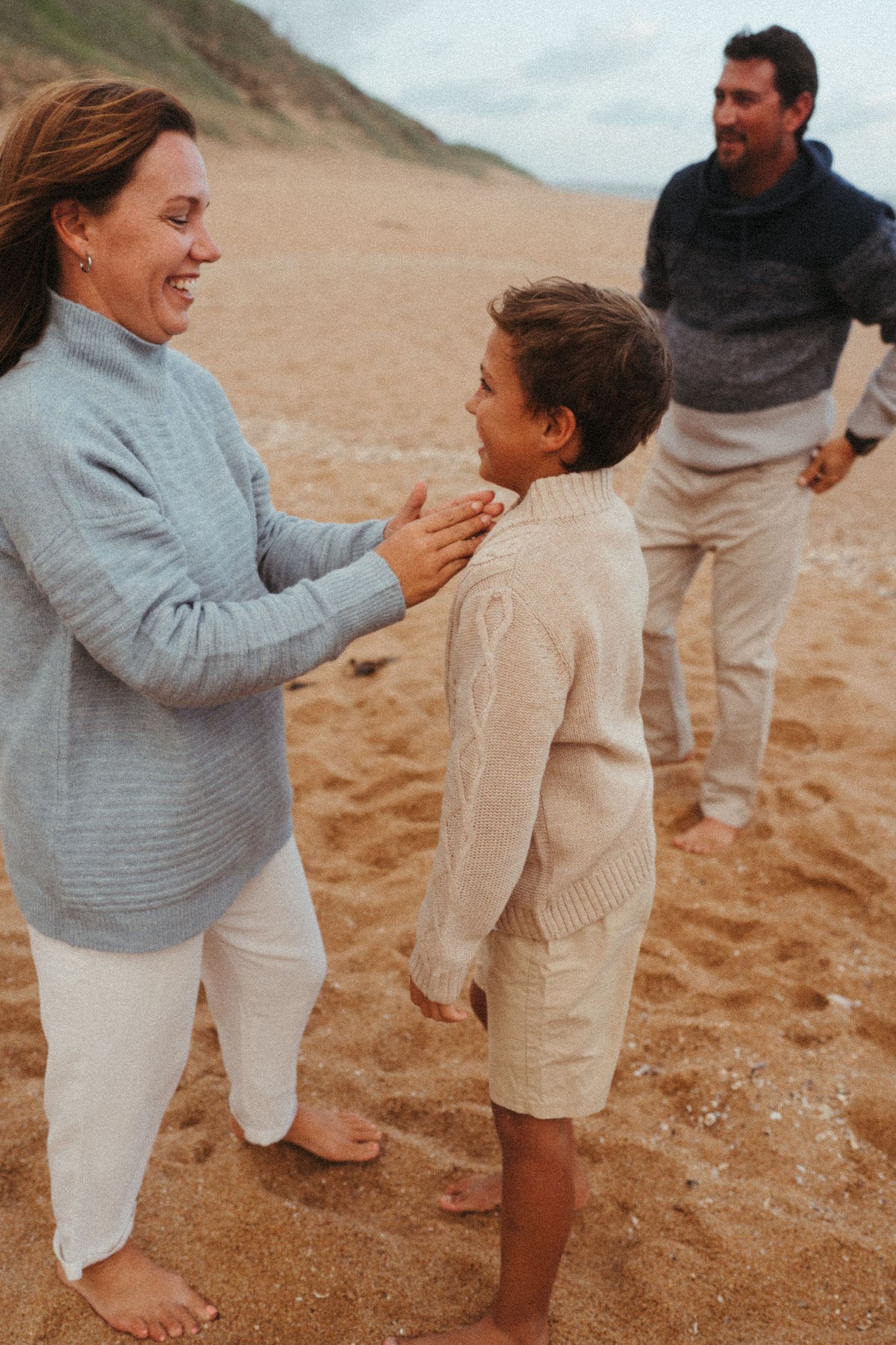 Family members in coordinated outfits sharing playful moments on the beach.