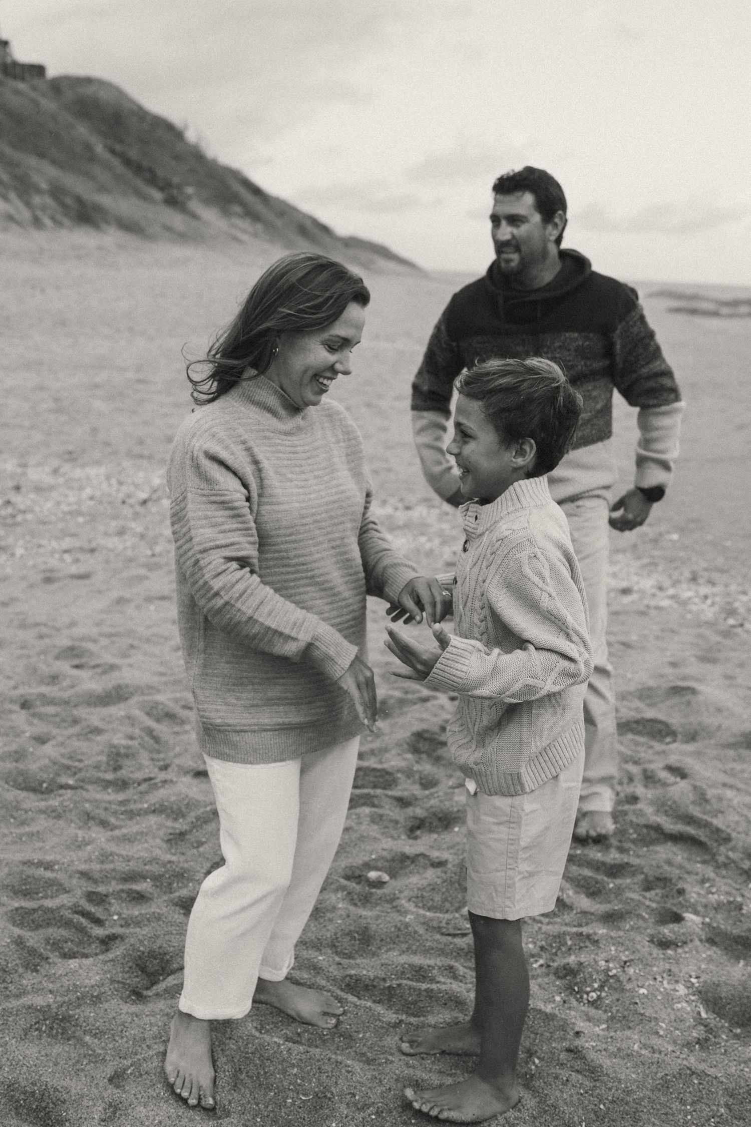 Black and white photo of a family sharing joyful moments on a beach.
