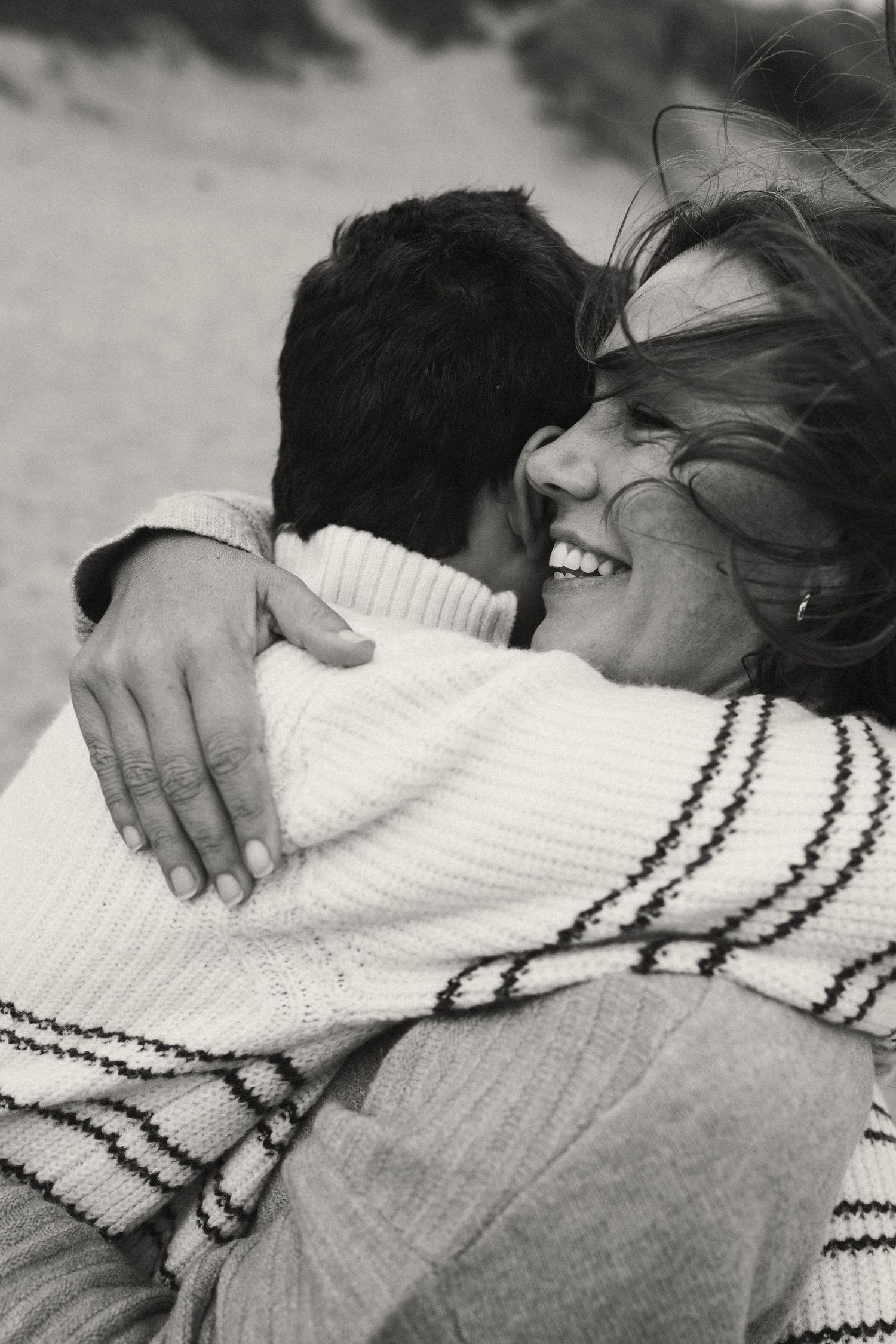 Black and white photo of a tender hug showing a white knit sweater with dark stripes.
