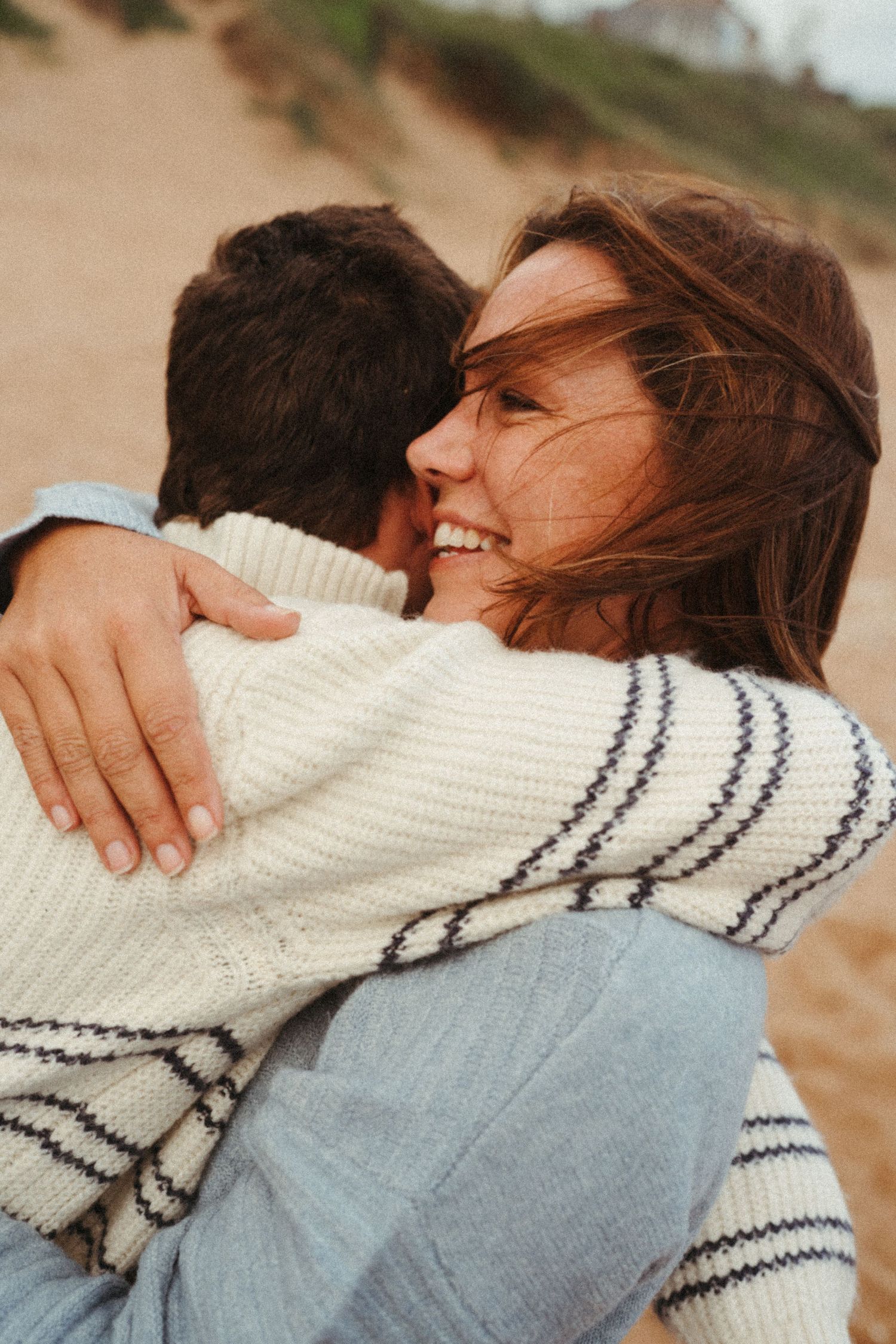 Close embrace captured in warm tones showing a white striped sweater against blue clothing.