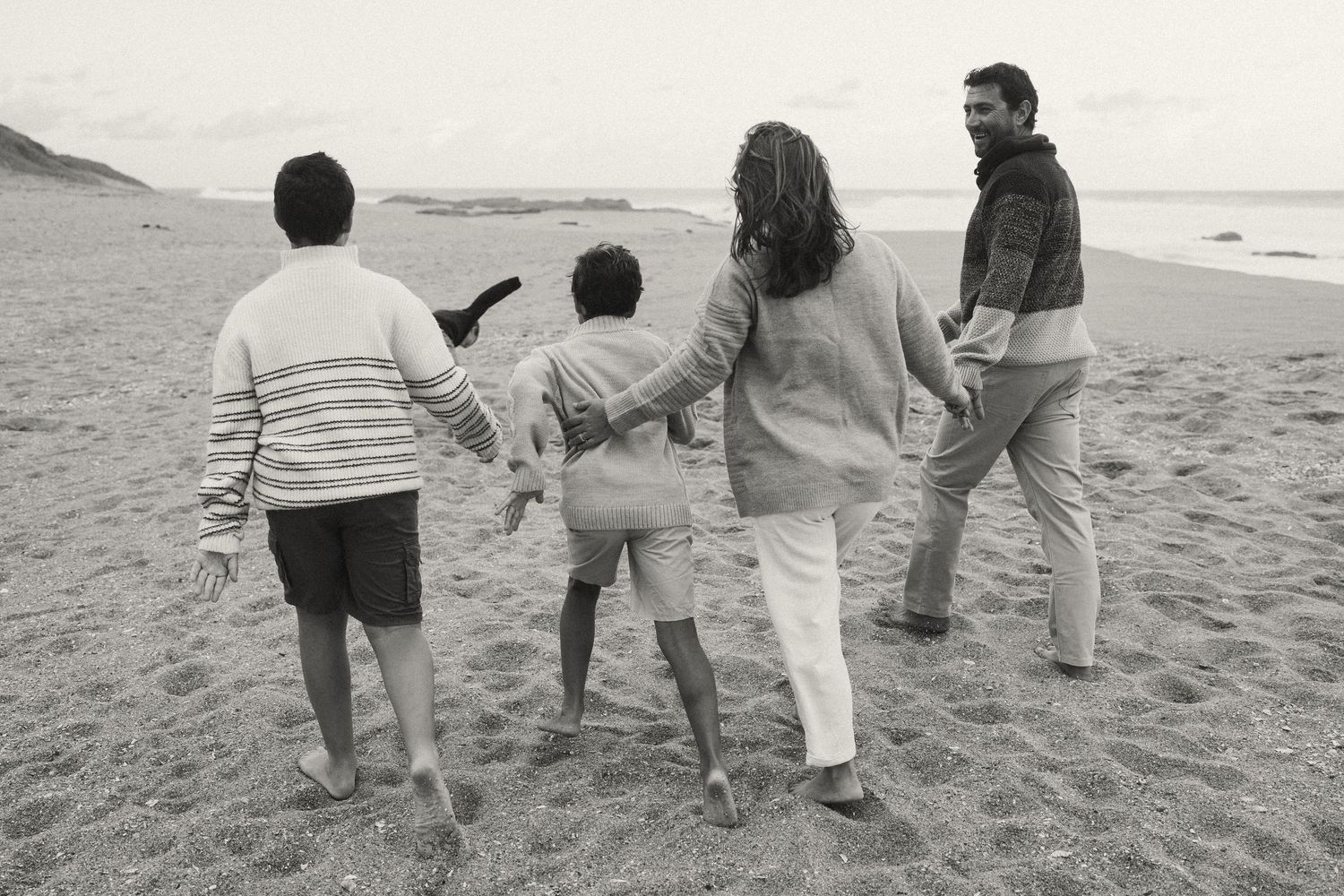 Group walking together along a scenic beach shoreline in casual wear.