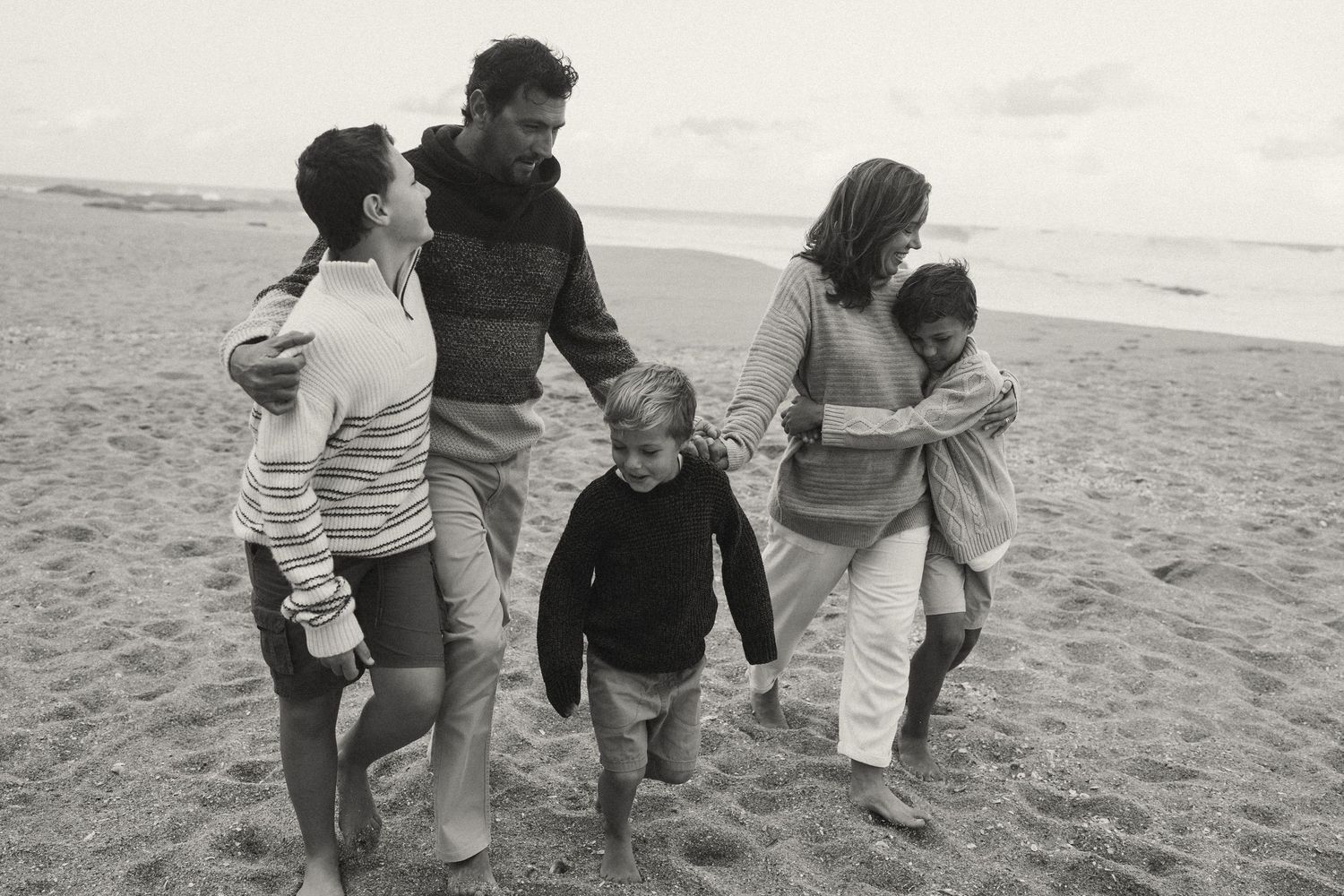 Group walking in sync along the shoreline wearing casual beach attire.