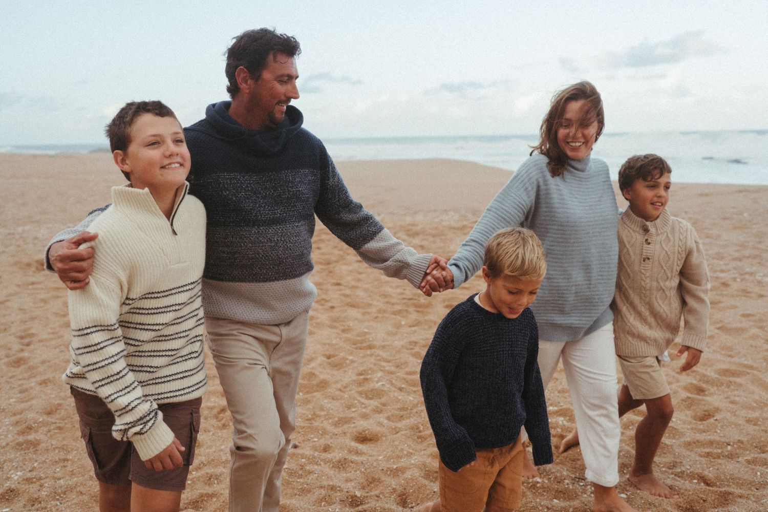 People enjoying a casual stroll on the beach in comfortable clothing.