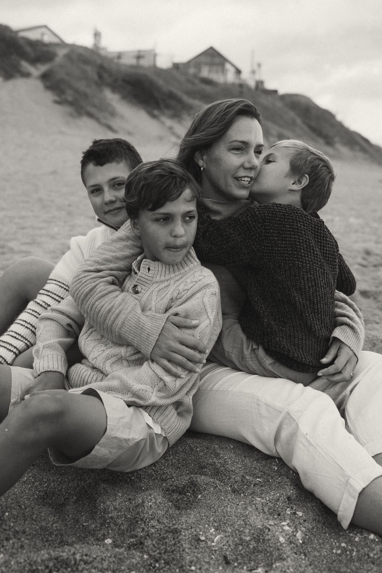 Black and white beach portrait showing people reclining on sand near coastal cliffs.