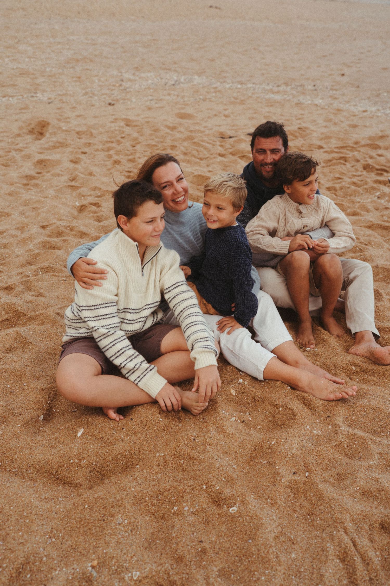 Warm-toned photograph of people lying together on beach sand.