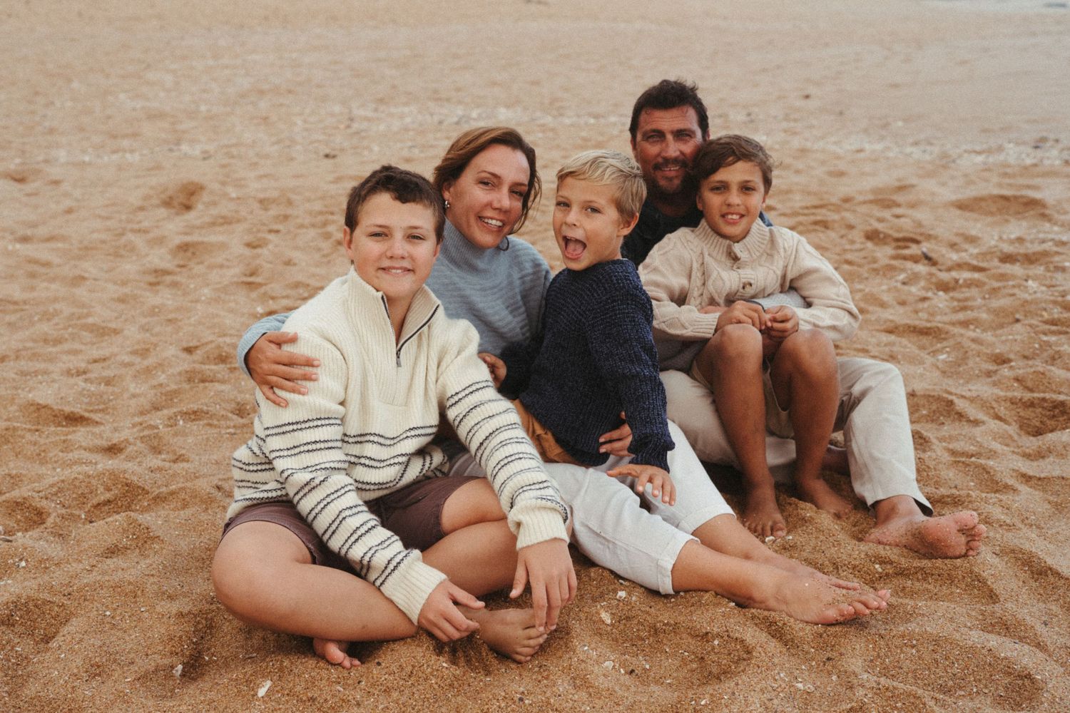 A group relaxes together on golden sand at the beach during daytime.