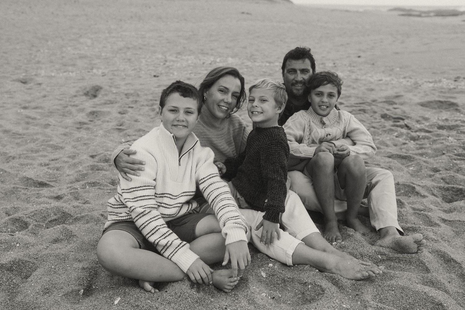 A group plays together on a sandy beach on an overcast day.