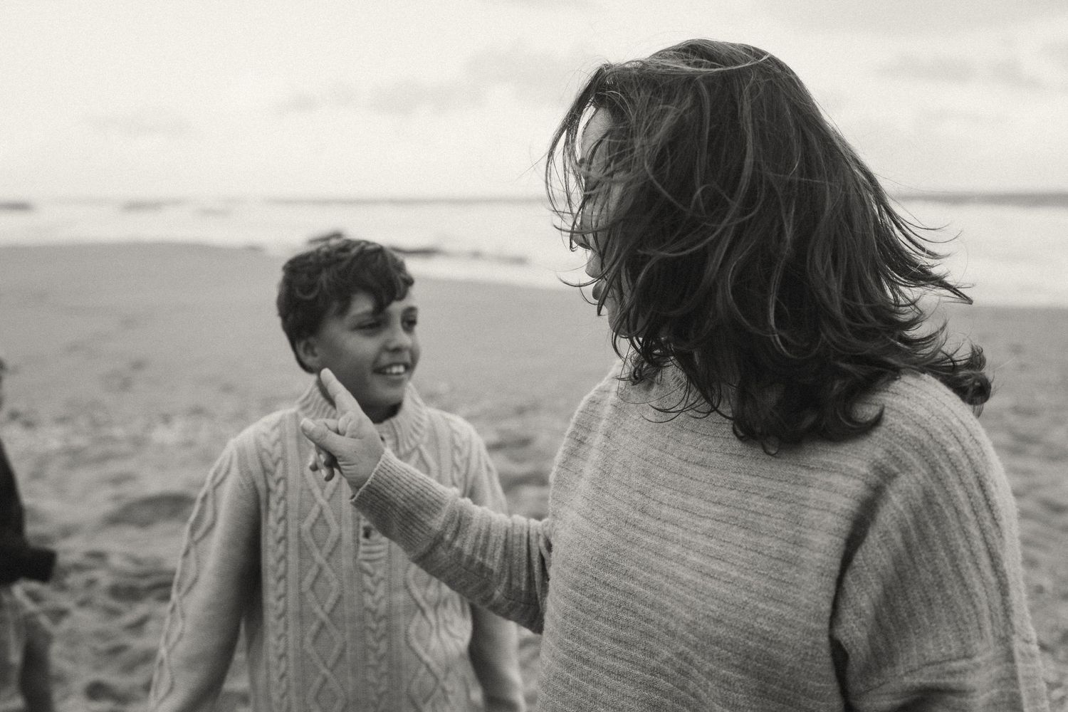 People enjoying a playful moment on a cloudy beach.
