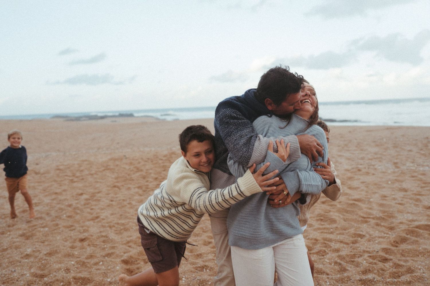 Friends sharing a joyful group hug on the shoreline.