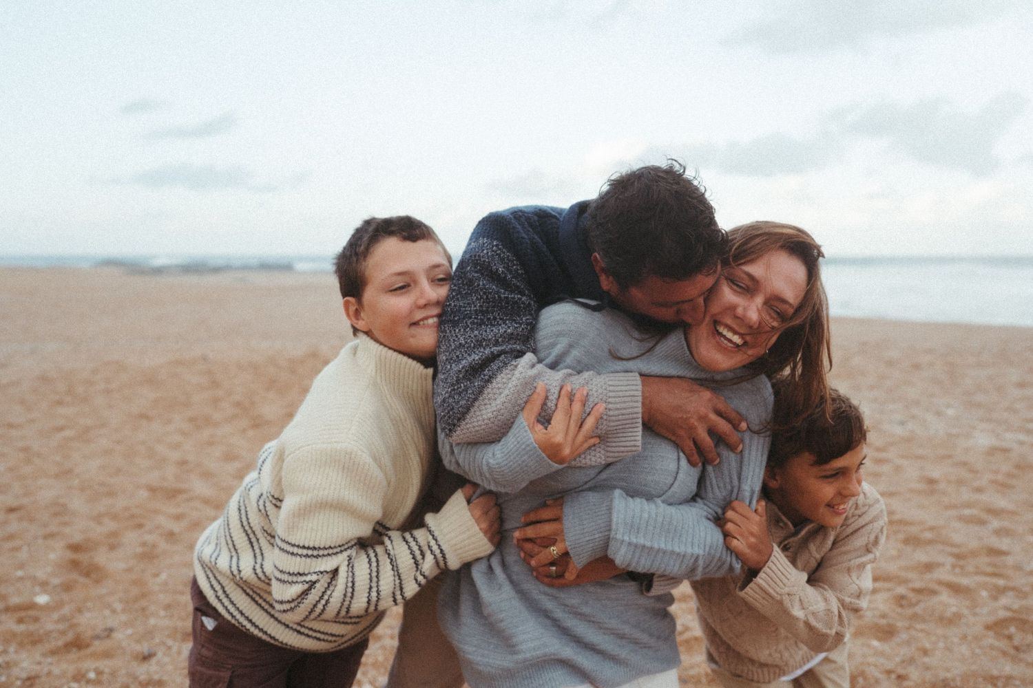 Friends huddled together in an energetic embrace on the beach.