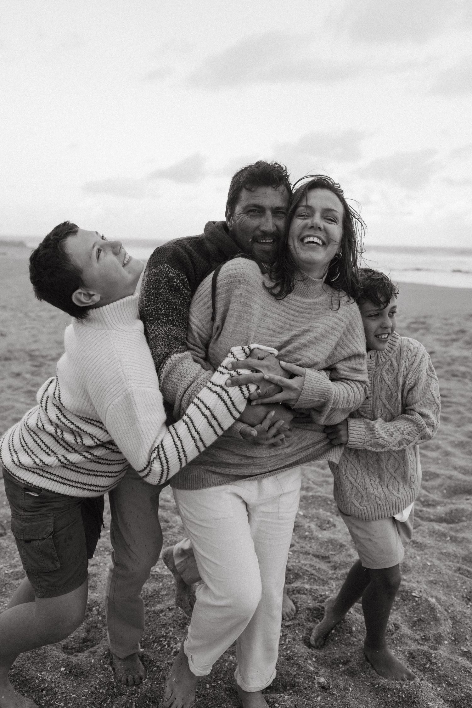 Group caught in a candid moment of laughter and hugs on the beach.