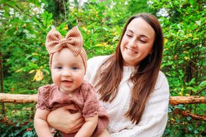 An outdoor portrait in a wooded setting with blooming flowers and greenery.