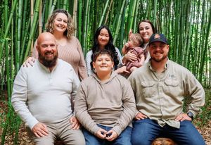 A group poses together in front of a lush bamboo forest backdrop.
