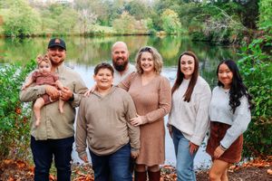 A group poses together by a serene lake surrounded by autumn foliage.