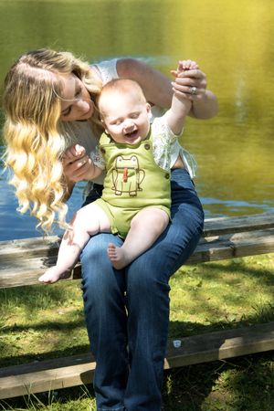 Candid moments captured on wooden bench by lake during golden hour photography session.