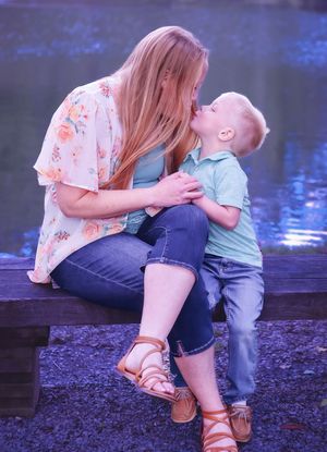 Parent and child bonding together on shoreline during outdoor photo session.