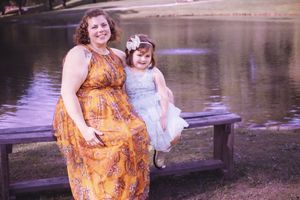 Lakeside family photography session featuring orange floral dress against natural water backdrop.