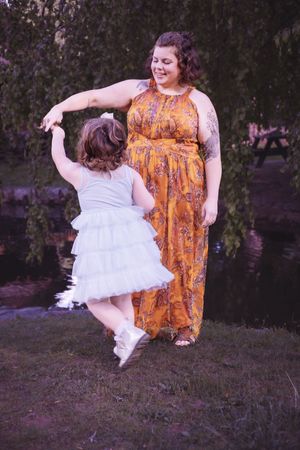 Playful outdoor photography session showing movement and joy near a lake at sunset.