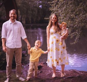 Family walks together along waterfront path during sunset photo session.