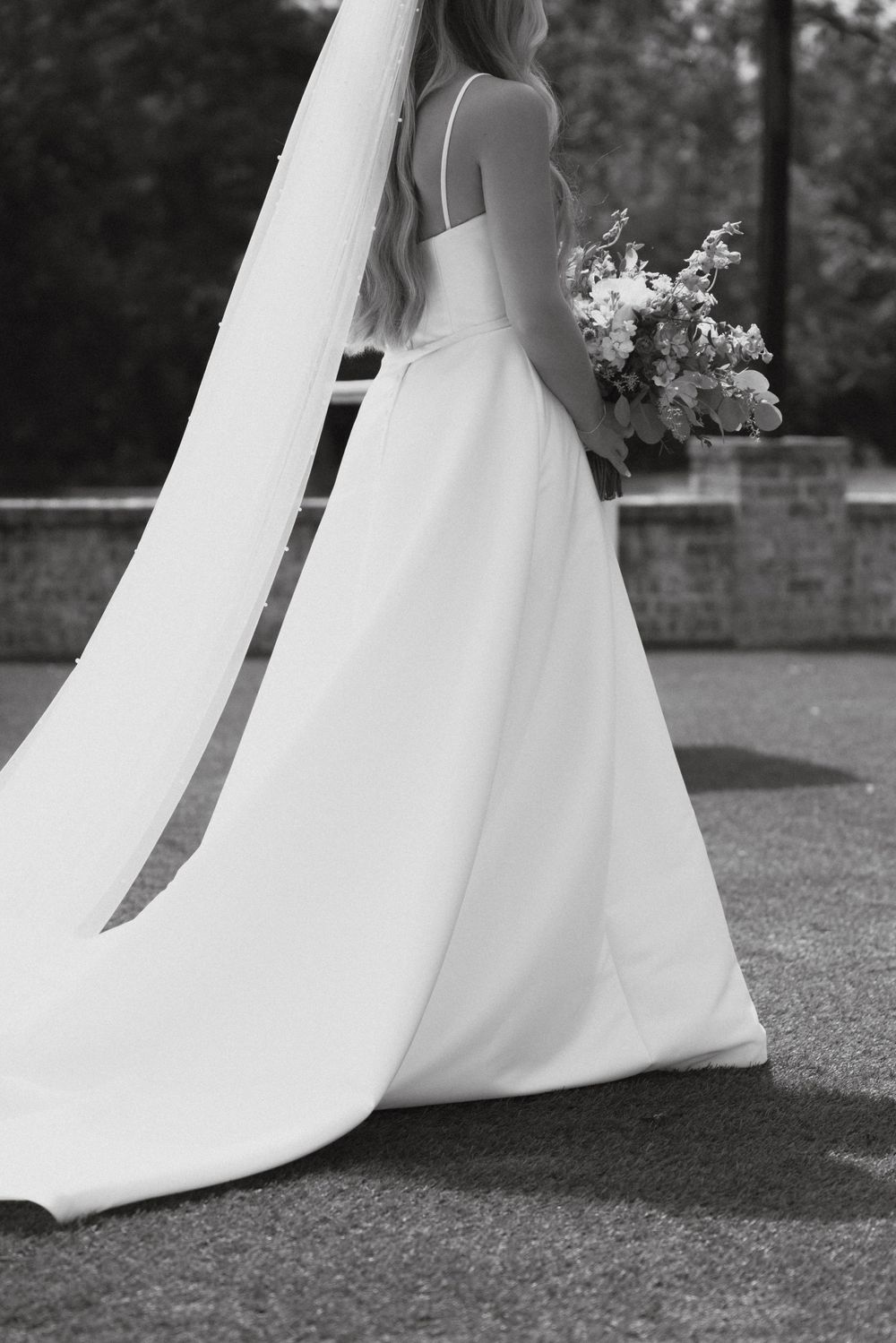 Black and white photo showcasing the elegant back detail and train of a wedding gown.