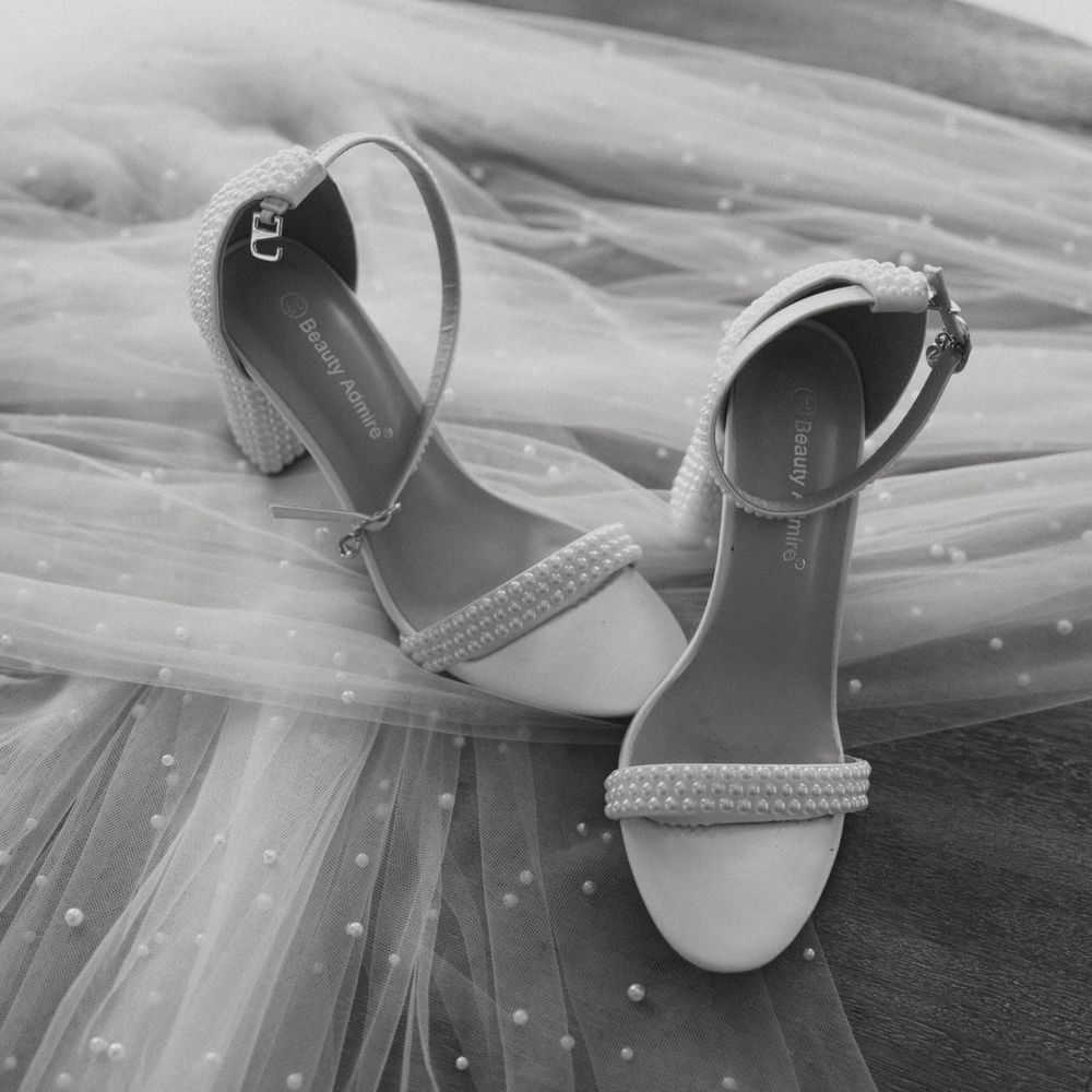 Elegant white wedding sandals with pearl detailing in black and white.