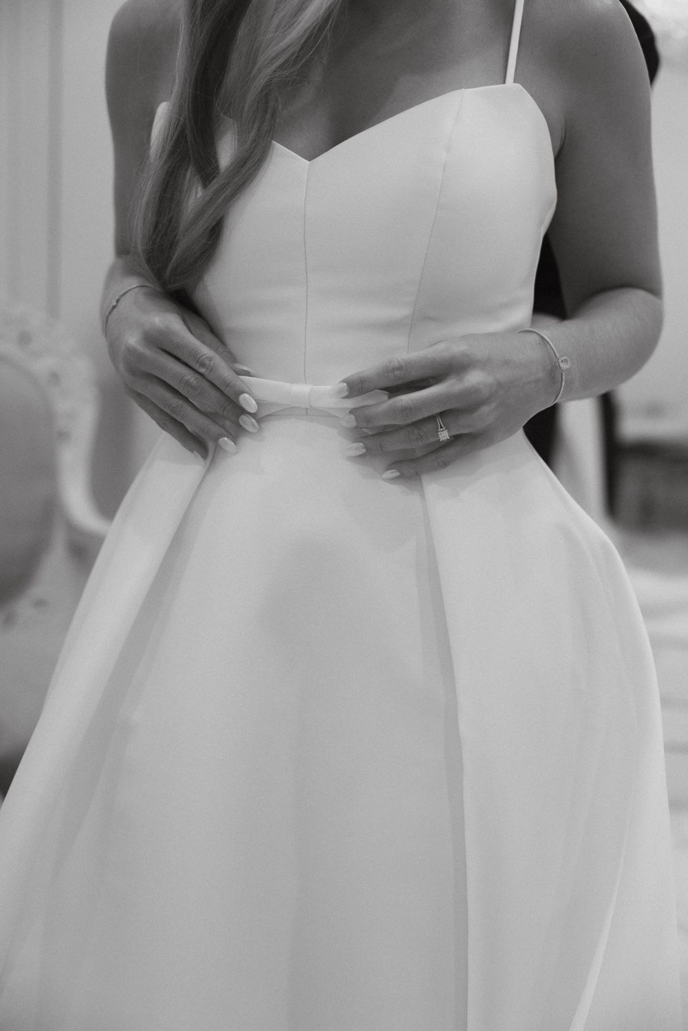 Close-up of bride's waist in white wedding dress showing pleated detail.